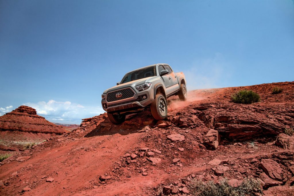 a 2018 Toyota Tacoma crawling down a sandy red hill