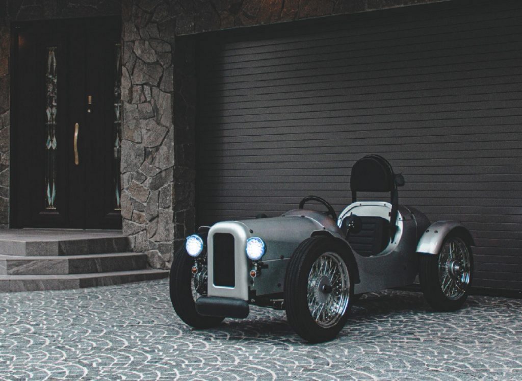 A silver Blaze EV Classic by a stone-lined garage