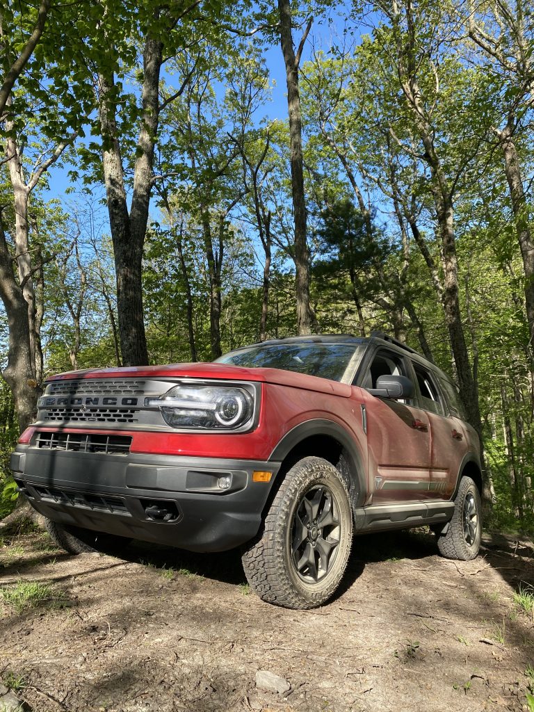A red 2021 Ford Bronco Sport parked on top a rock in the forest 