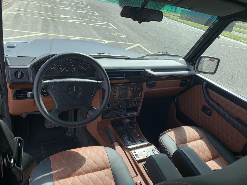 The brown-and-black-leather-upholstered front seats and wood-trimmed dashboard of a modified 1995 Mercedes-Benz G320