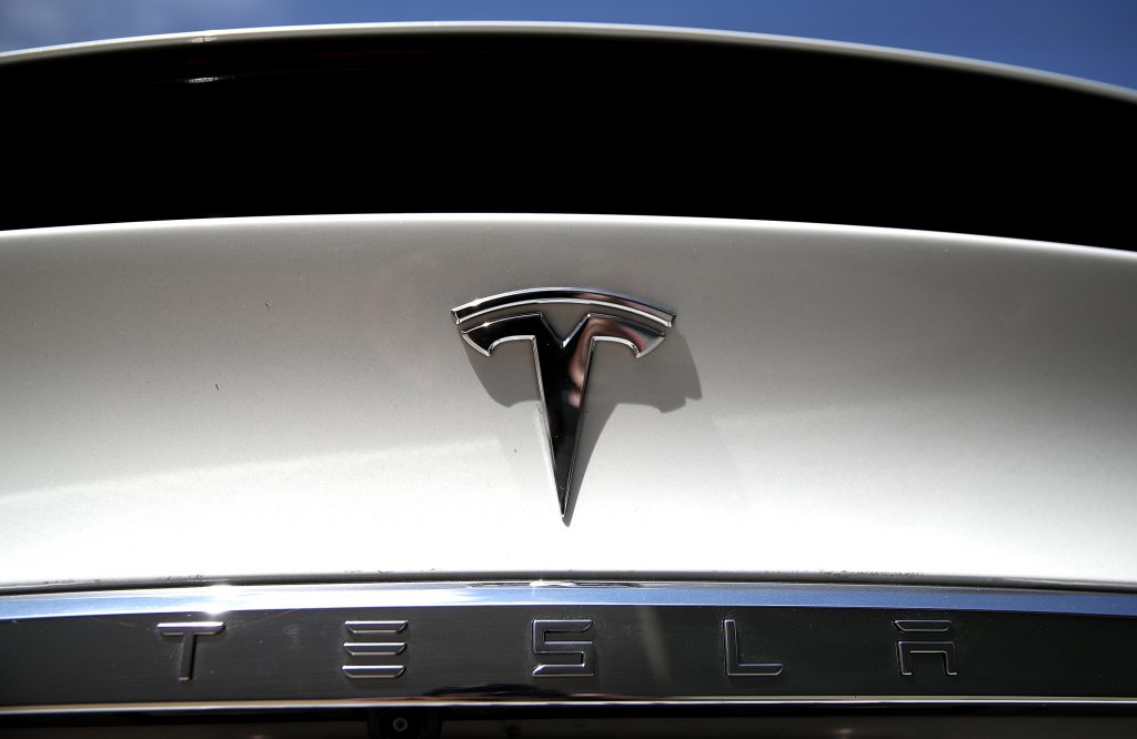 Silver Tesla logo badge on a white Model S
