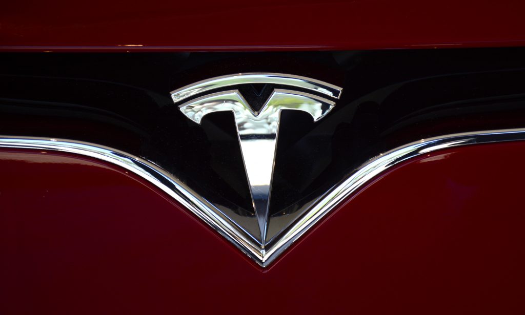 a chrome Tesla emblem on a red EV