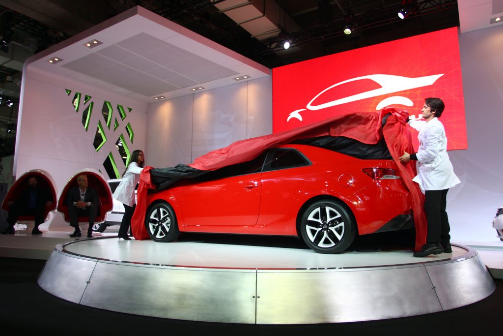 A red kia forte coupe being unveiled
