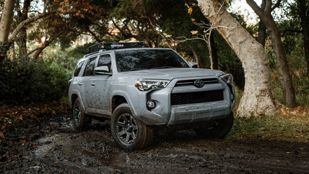 A silver 2021 Toyota 4Runner SUV driving through muddy woods