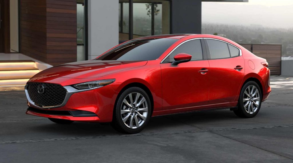 A red 2021 Mazda3 Premium by a white-and-brown-wood house