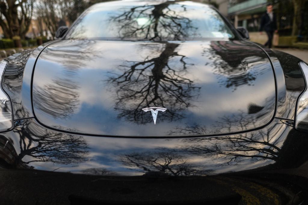 The front of a black Tesla sedan with hood and badge visible