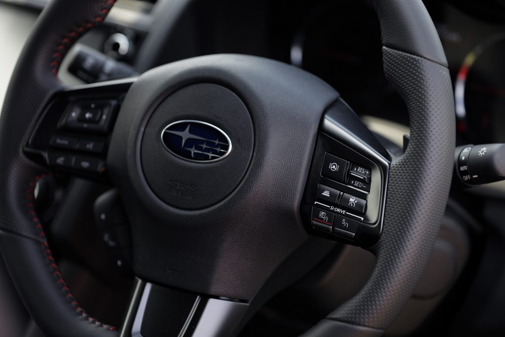 The leather-wrapped, red-stitched steering wheel of a Subaru WRX