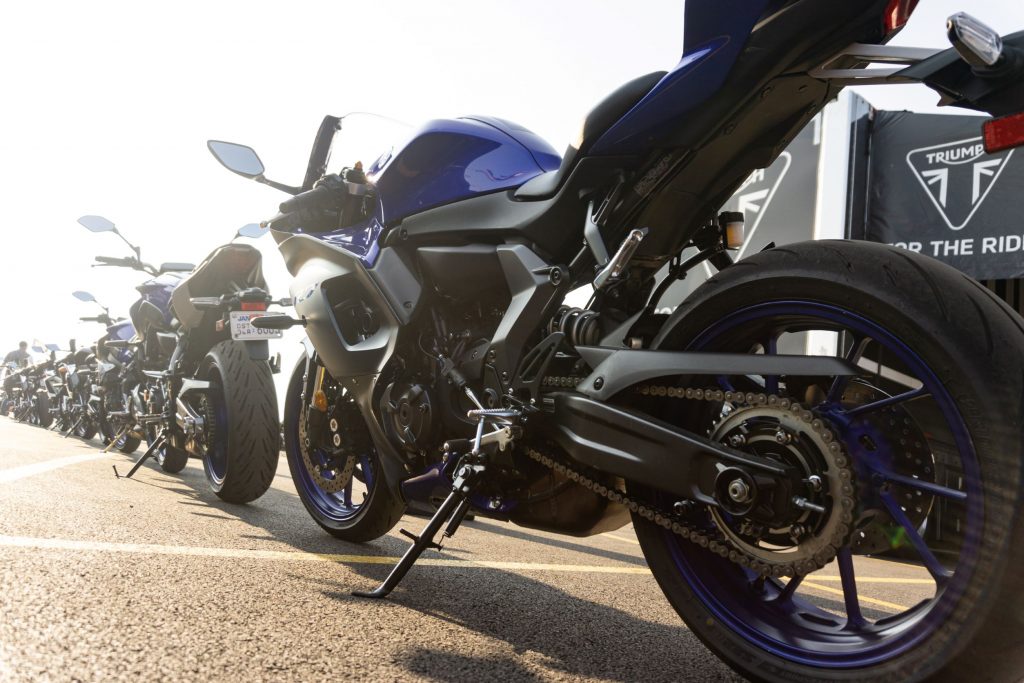 A low-angle rear 3/4 view of a blue-and-black 2022 Yamaha YZF-R7 behind a line of other bikes