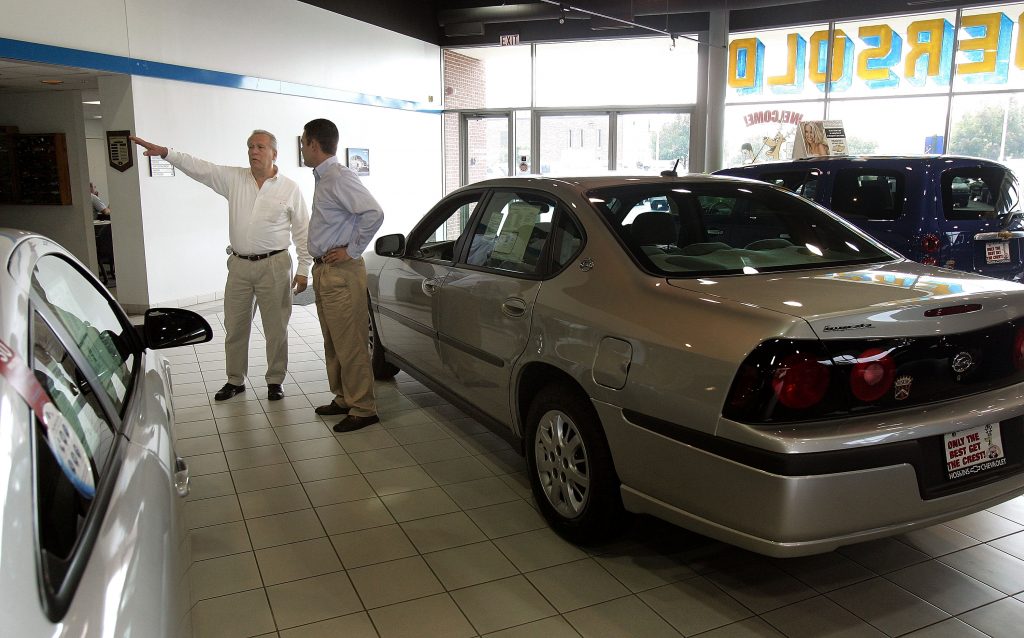 Sales and leasing consultant assists a customer in the new-car showroom
