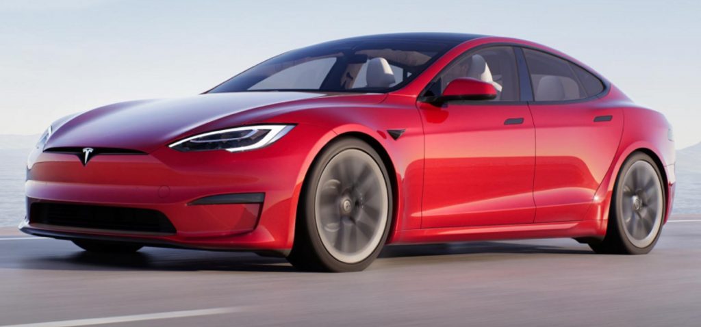 A red 2022 Tesla Model S Plaid driving down a road