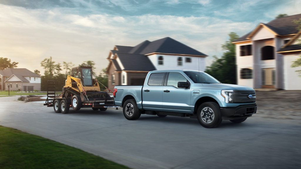 Blue 2022 Ford F-150 Lightning Pro towing a trailer. Pre-production model with available features shown. Available starting spring 2022. Max towing varies based on cargo, vehicle configuration, accessories and number of passengers.