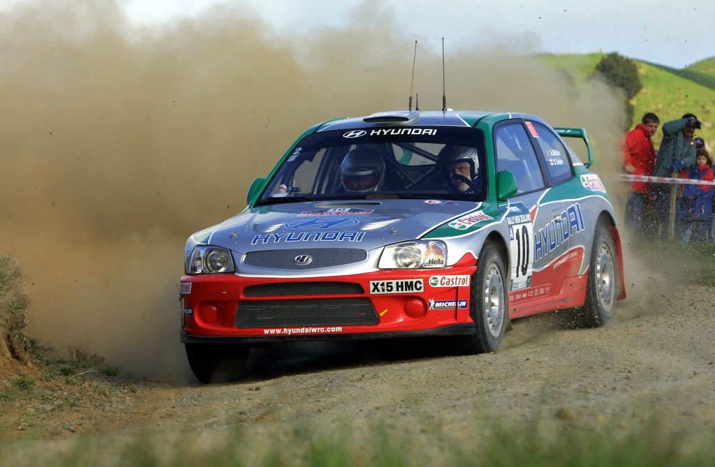 Dean MacRae in a Hyundai Accent rally car kicking up dirt mid-corner
